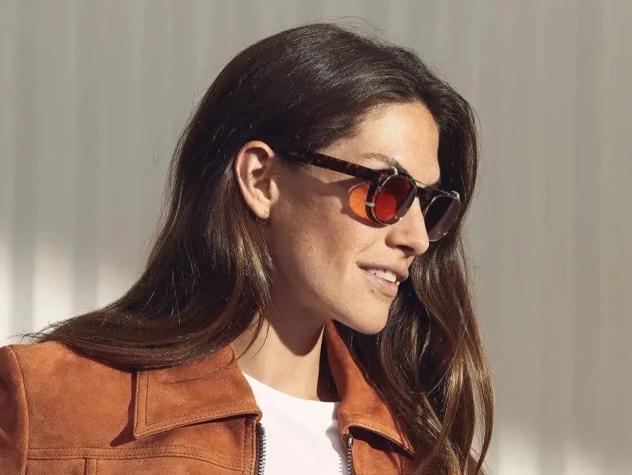 Dame draagt Moscot zonnebril met rood oranje glazen bij Teeling Optiek Amsterdam